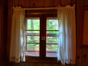 Une fenêtre à cadre en bois, ornée de rideaux blancs et dotée d’un loquet.