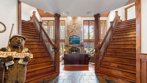 A wooden staircase leading to a lobby with a stone fireplace and a welcome sign. - Luxury Secluded 7000 s/f 5-Acre Estate with 200' Private Beach Close-in Hot-Tub (Post Falls)