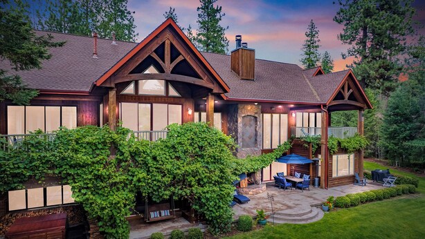 A large, wooden house with a stone fireplace, a covered porch, and a well-maintained garden. - CDAs Finest Secluded Waterfront Estate 7000 Sq ft 5 Forested Acres-Close to town (Post Falls)