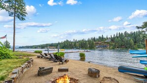 A lakeside deck with a fire pit, lounge chairs, and kayaks. - CDAs Finest Secluded Waterfront Estate 7000 Sq ft 5 Forested Acres-Close to town (Post Falls)