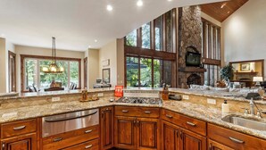 A spacious kitchen with a large island, stone accent wall, and a stone fireplace. - CDAs Finest Secluded Waterfront Estate 7000 Sq ft 5 Forested Acres-Close to town (Post Falls)