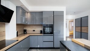A modern kitchen with sleek cabinetry, a built-in oven, and a flat-screen TV.