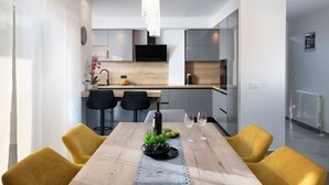 A modern dining area with a wooden table, yellow chairs, and a pendant light.