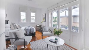 A modern living room with a sofa, armchairs, a coffee table, and a view through large windows. - Designer Styled Studio in Central Trendy Glebe (Glebe)
