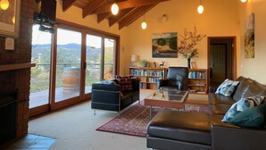 A spacious living room with a fireplace, a large bookshelf, and a comfortable seating area. - Kurrajong Views Jindabyne (Jindabyne)