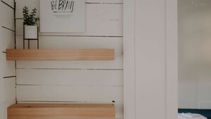 A room with white wooden walls, a 'Be Brave' poster, and three wooden shelves. - Cozy remodeled modern farmhouse for up to 10, with secondary room for up to 30 (New London)