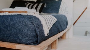 A bed with a blue patterned bedspread, white and blue pillows, and a wooden headboard. - Cozy remodeled modern farmhouse for up to 10, with secondary room for up to 30 (New London)