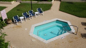 En swimmingpool med en skylt som visar att den är 90 cm djup, omgiven av en innergård med tegelbeläggning och blå stolar.