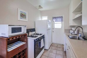 Cocina compacta con microondas, estufa, refrigerador y un lavamanos pequeño.