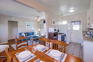 Un espacio habitable compacto con comedor, kitchenette y sala de estar con sofá azul.