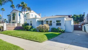 A residential house with a front lawn, a driveway, and a gated backyard. - Charming PB bungalow, pet-friendly yard, parking (San Diego)