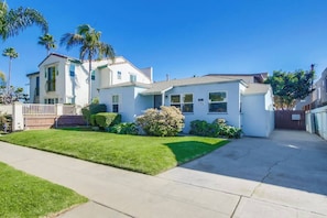 A residential house with a front lawn, a driveway, and a gated backyard. - Charming PB bungalow, pet-friendly yard, parking (San Diego)