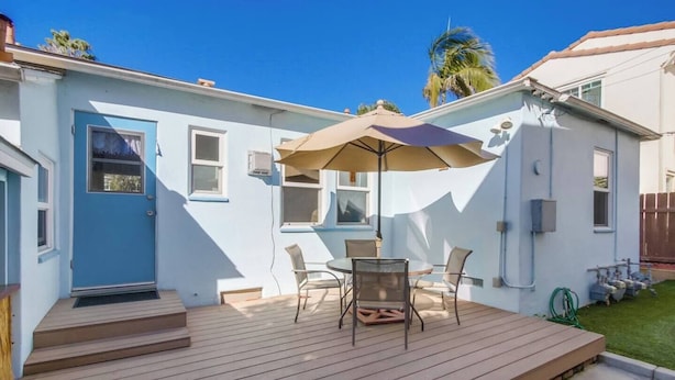 A residential deck with a table and chairs, a door, and a window. - Charming PB bungalow, pet-friendly yard, parking (San Diego)