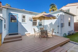 Une terrasse d’habitation avec une table et des chaises, une porte et une fenêtre.