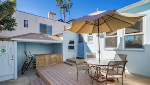 A patio with a table and chairs, a covered area with a chair, and a bicycle leaning against a wall. - Charming PB bungalow, pet-friendly yard, parking (San Diego)
