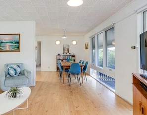 A modern living room with a sofa, coffee table, and a dining area with chairs and a table.