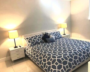 Une chambre à coucher avec un lit, deux tables de chevet et deux lampes.