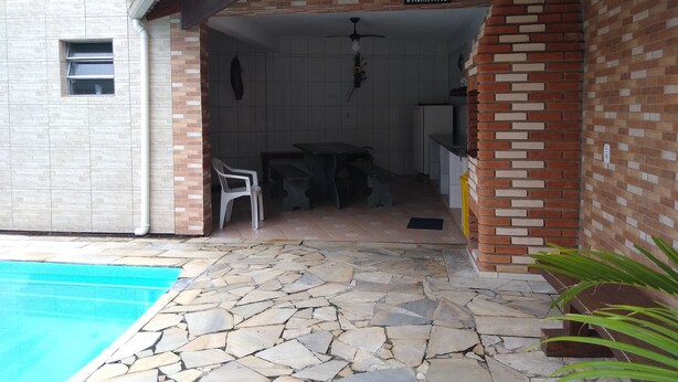 Ein überdachter Patio-Bereich mit Steinboden, einem Pool und einem Schild mit der Aufschrift 'Cantinho do Churro'.