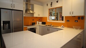 Una cocina moderna con armarios blancos, electrodomésticos de acero inoxidable y una pared de acento naranja.