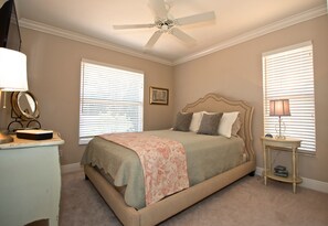 A bedroom with a bed, a ceiling fan, a bedside table with a lamp, and a dresser. - 5 Minute Walk To Beach & JW Marriott, Fantastic SW Pool Exposure, Designer Home (Marco Island)