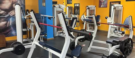 A gym with weightlifting equipment, a mirrored wall, and motivational posters.
