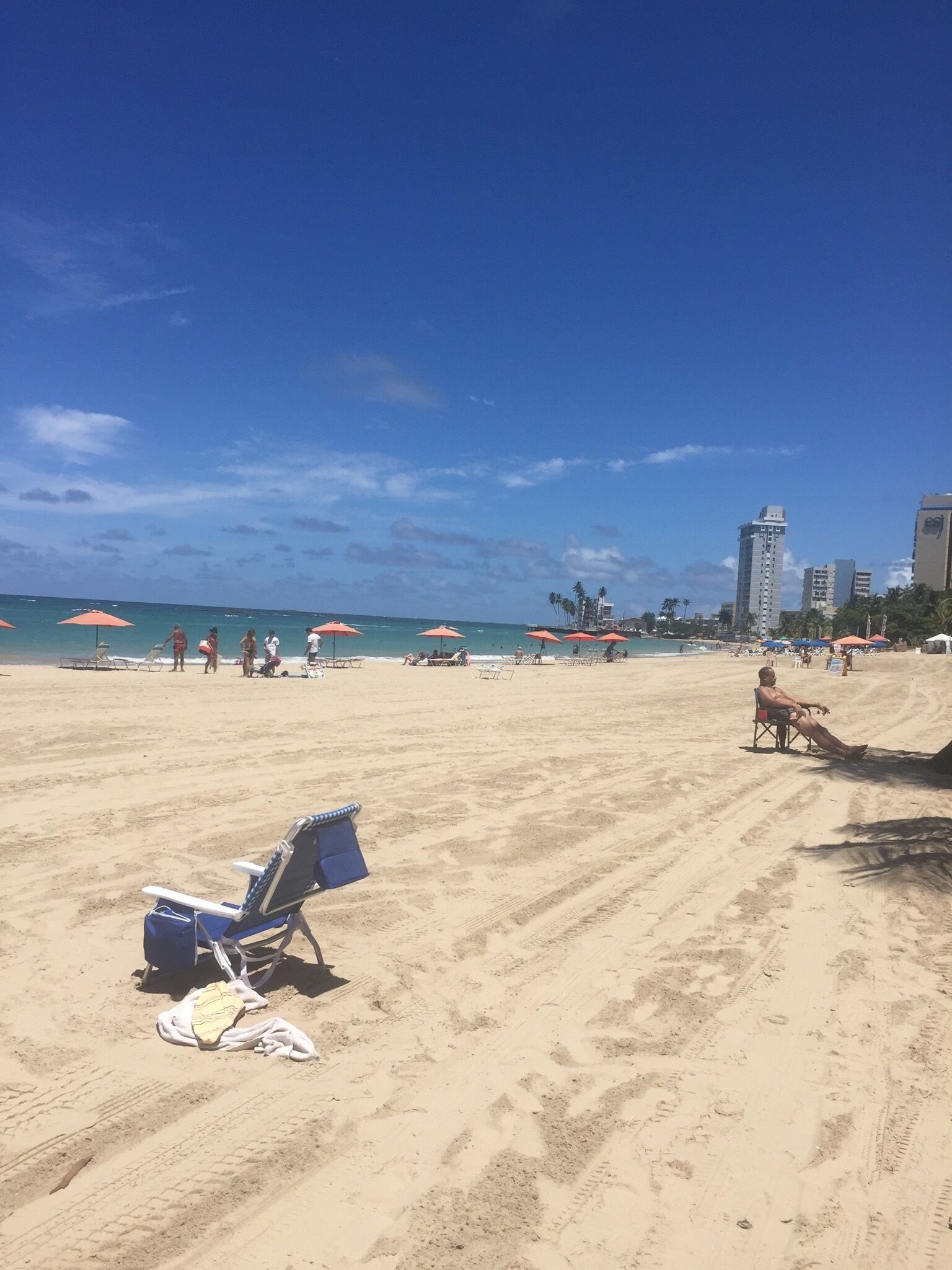 A beach with clear skies, a few umbrellas, and a few people.