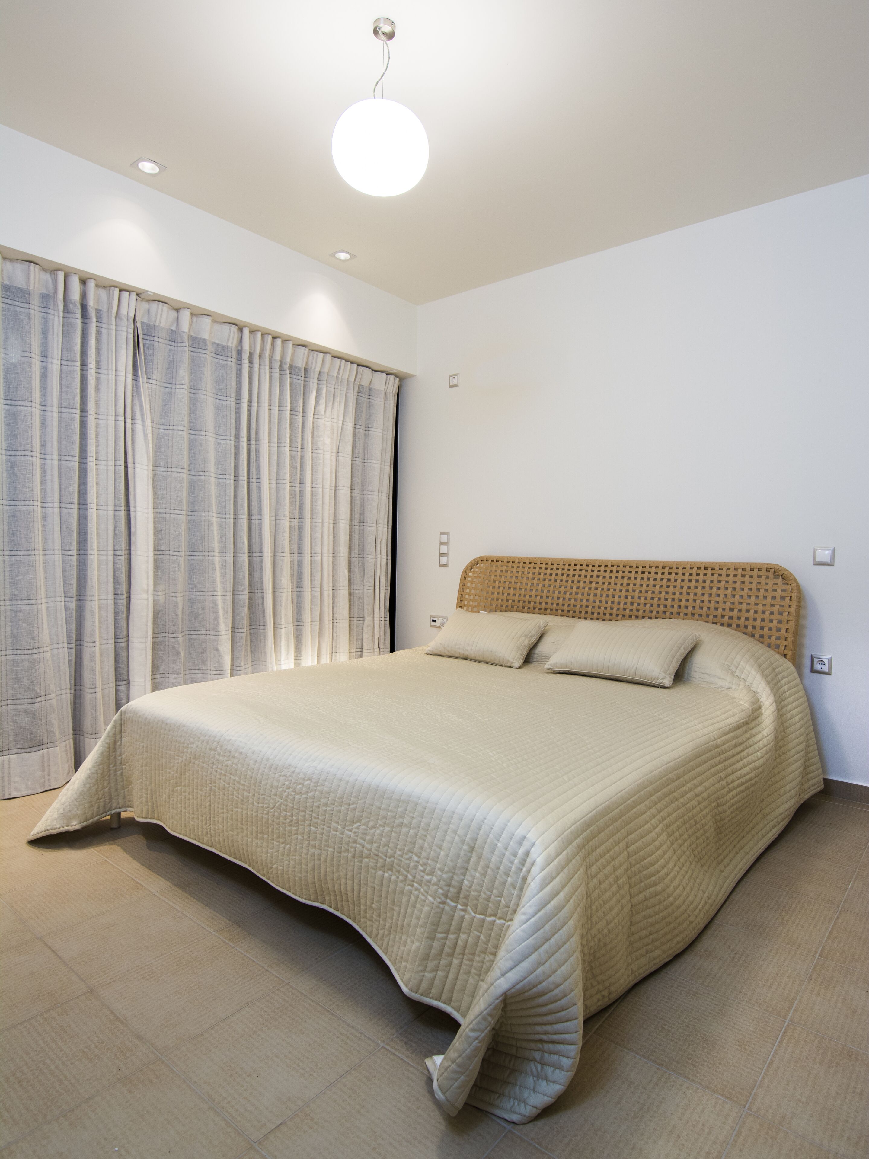 Une chambre à coucher avec un grand lit, une tête de lit et une fenêtre avec des rideaux.