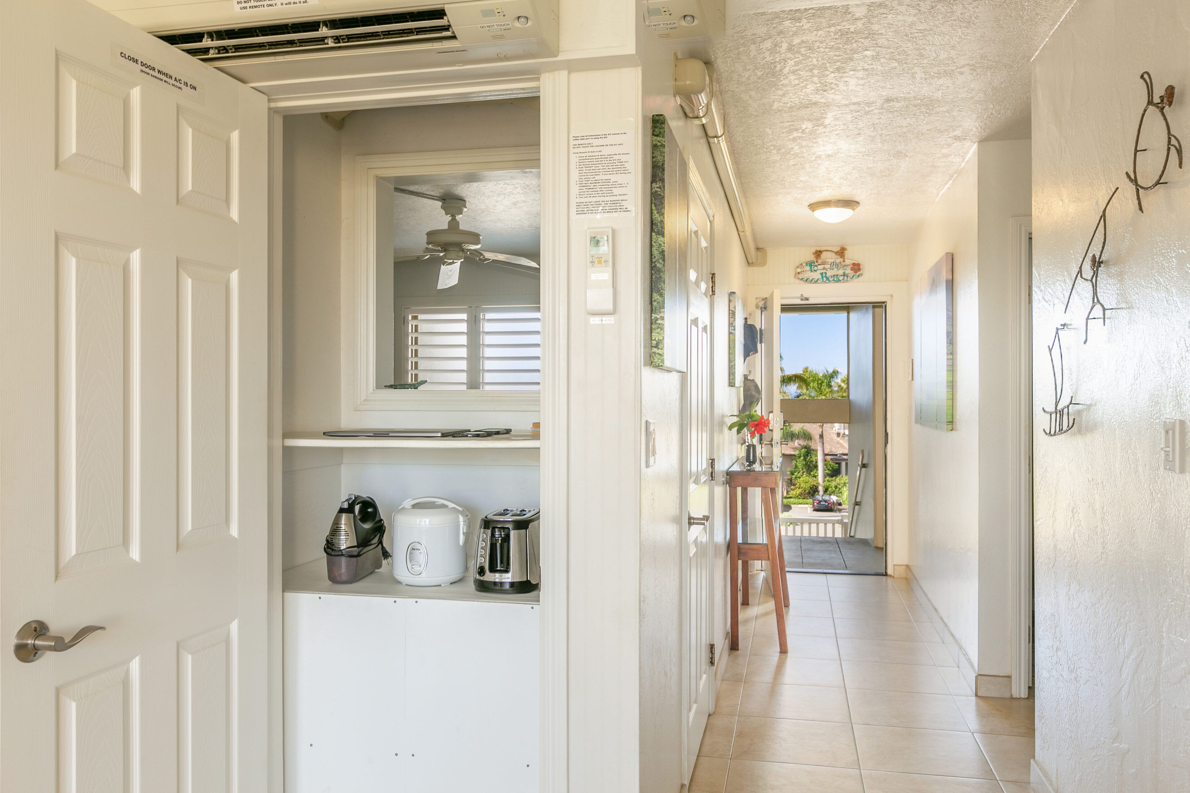 A hallway with a white door, ceiling fan, and a small table with a vase.