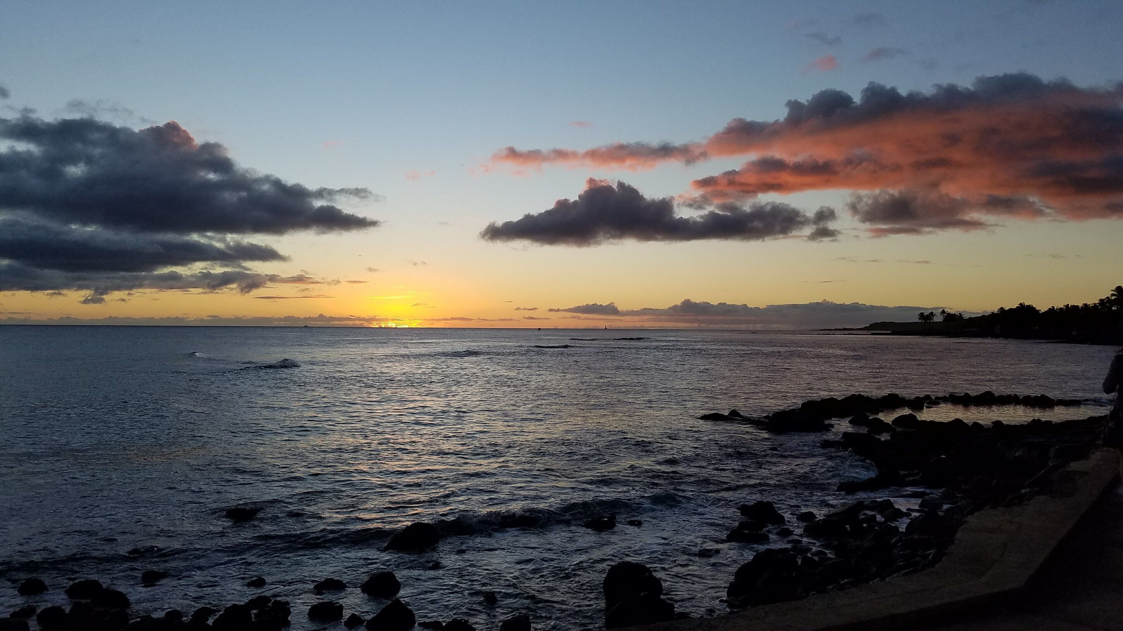 A coastal sunset with a rocky shoreline.