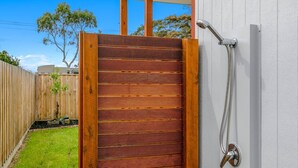 A wooden gate with horizontal slats, a metal showerhead, and a white wall. - Absolutely Beach - with private swimming pool (Cowes)