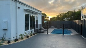 A modern house with a large window, a concrete patio, and a swimming pool. - Absolutely Beach - with private swimming pool (Cowes)