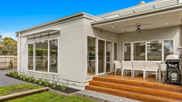 A modern house with a patio, large sliding glass doors, and a barbecue grill. - Absolutely Beach - with private swimming pool (Cowes)