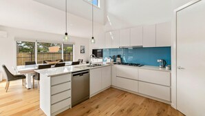 A modern kitchen with white cabinetry, a central island, and a blue backsplash. - Absolutely Beach - with private swimming pool (Cowes)