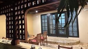 Une pièce avec une cloison en bois, un coin repas avec des chaises et une table, et une grande fenêtre donnant sur un beau paysage.