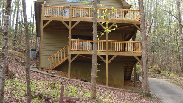 Une cabane à deux étages avec un balcon, entourée d’arbres.