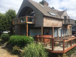 Una casa de dos pisos con un balcón grande en el segundo nivel y una chimenea.