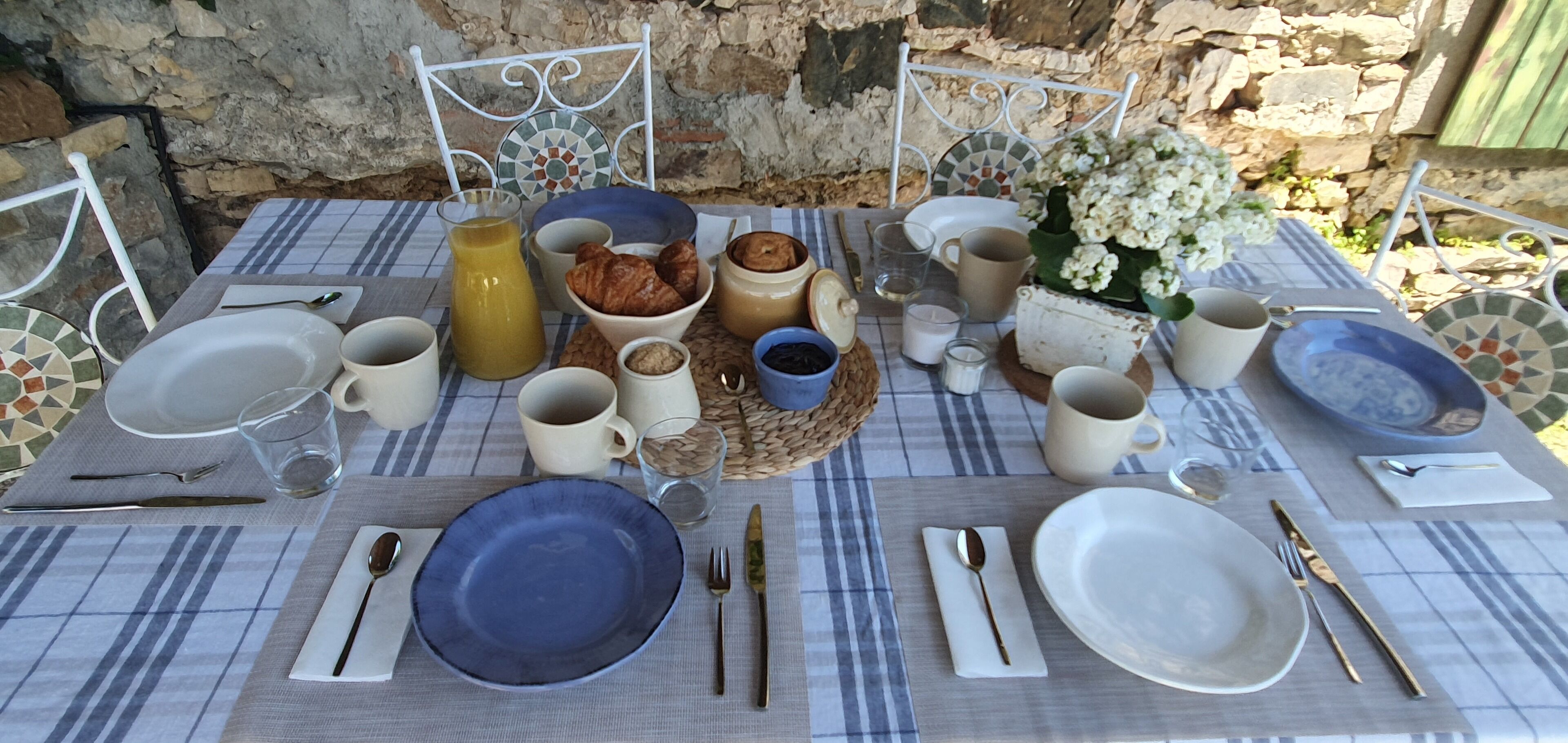 Ein Tisch ist für das Frühstück gedeckt, mit Tellern, Tassen und einem Saftkrug.