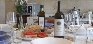 Mesa de jantar posta com taças de vinho, uma garrafa de vinho e um prato de pão com tomate.