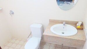 Un baño con inodoro, lavamanos y espejo.