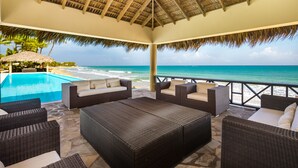 Un'area relax all'aperto con mobili in vimini, una piscina e vista sull'oceano.
