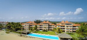 A resort with multiple buildings, a swimming pool, and a beach.