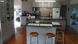 Une cuisine moderne dotée d’un îlot central, d’appareils électroménagers en acier inoxydable et de tabourets de bar.