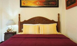 A bed with a wooden headboard, a red bedspread, and two yellow pillows. - Teak Room with Mountain View (Tambon Nong Kwai)