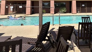A pool area with lounge chairs and a building with a tiled roof.