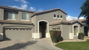 A two-story house with a garage, a covered entryway, and a well-maintained lawn.