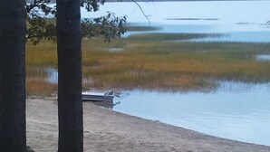 Un lac paisible, avec un bateau amarré sur la rive, entouré d’arbres et de zones herbeuses.