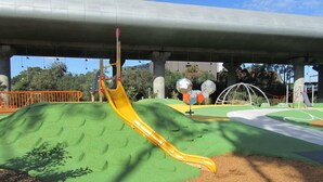 A playground with a yellow slide, green play area, and a bridge structure. - Comfy One-Bedroom Unit Between City and Airport (Travancore)