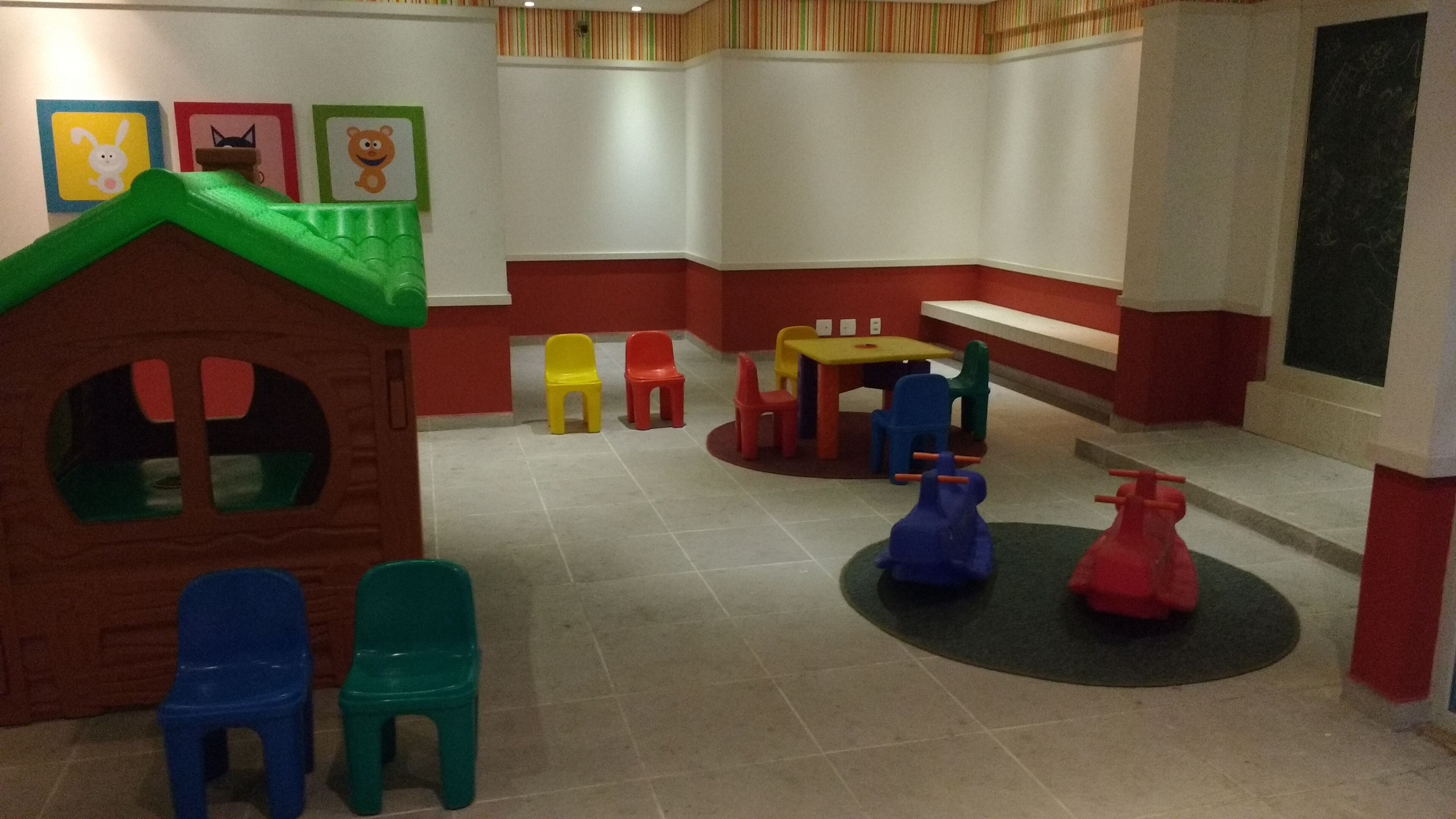 A children's play area with a playhouse, colorful chairs, and a small table.