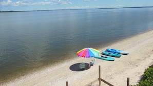Ein Strand mit Kajaks und einem bunten Sonnenschirm.
