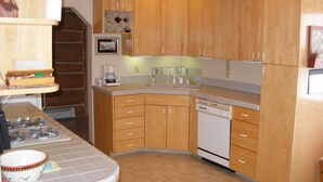 Una cocina con gabinetes de madera, lavavajillas integrado y estufa.
